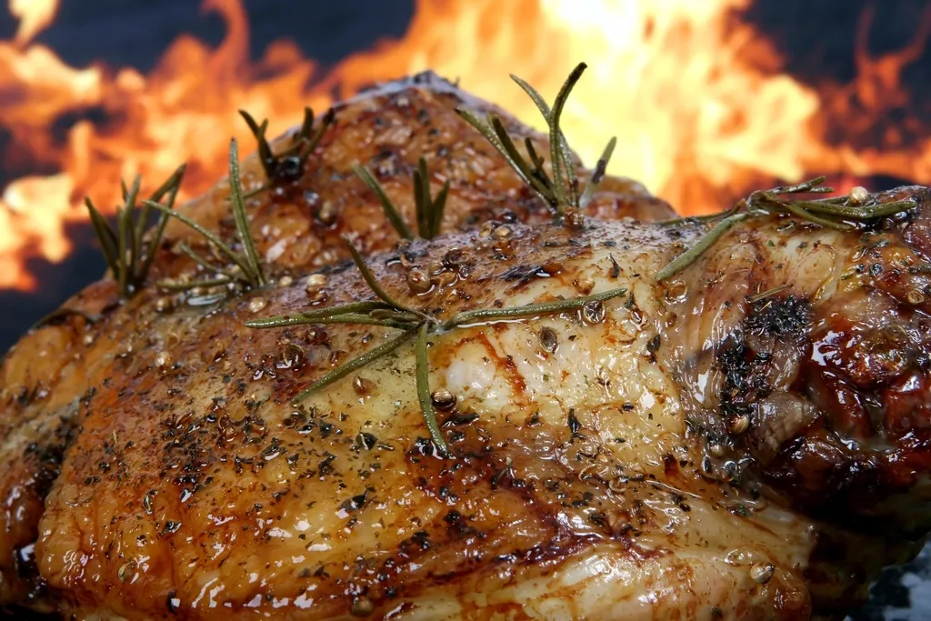 Pollo asado con romero, dorado, delante de las llamas