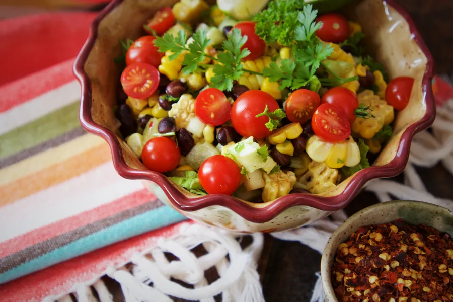 Ensalada de tomate cherry, maíz y hierbas en una fuente de cerámica