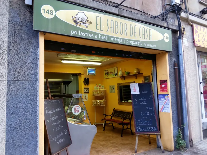 Fachada de El Sabor de Casa: rótulo verde oliva con el óvalo crema y el número 148, y dentro, paredes amarillas y el mostrador