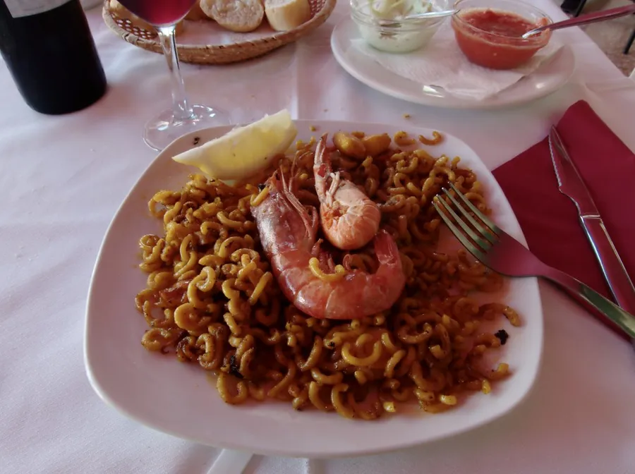 Plato de fideuà con una gamba encima y limón