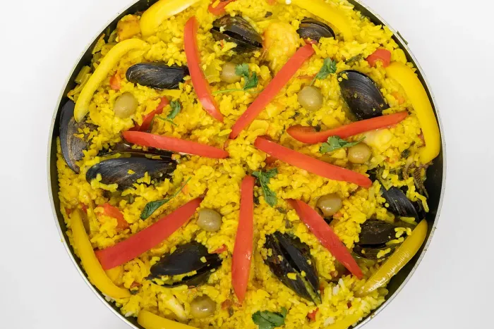 Paella de marisco vista desde arriba, con mejillones y tiras de pimiento rojo y amarillo